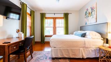 Une chambre à coucher avec un lit, un bureau, une chaise et un téléviseur fixé au mur.