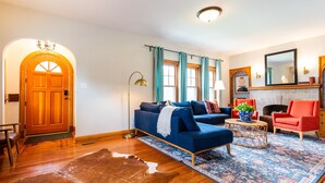 A living room with a sofa, armchairs, a coffee table, a fireplace, and a door. - 5BR w/ 6 King Beds + Hot Tub (Louisville)
