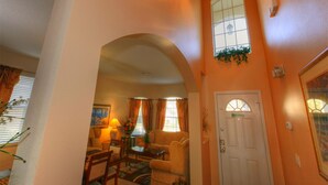 A living room with a sofa, coffee table, and lamp. There is a door with a window above it. - DISNEY AREA, Highlands Reserve SOUTH facing POOL, GAMES ROOM. SPECIALS AVAILABLE (Davenport)