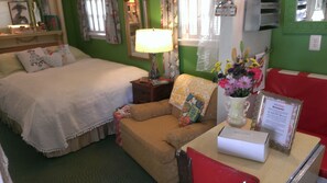 Une pièce confortable avec un lit, un petit canapé, une table ornée d’un vase de fleurs et une lampe.