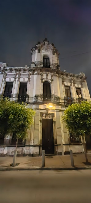 Een historisch gebouw met versierde architectuur, een opvallende ingang en een balkon met hekwerk.