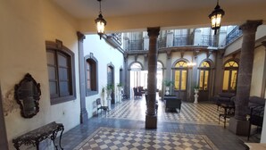A spacious lobby with checkered flooring, ornate columns, and classic furniture.
