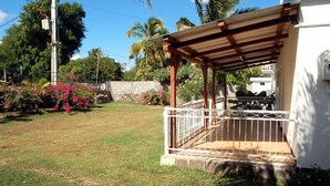 A covered outdoor area with a wooden pergola, a white railing, and a stone wall.