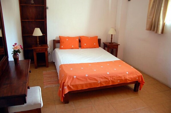 A bedroom with a bed, two nightstands, a wooden wardrobe, a desk, and a chair.