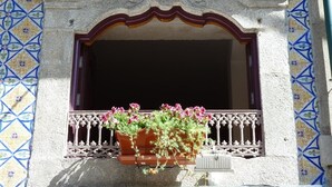 A building facade with a decorative window, a tiled wall, and a flower box.