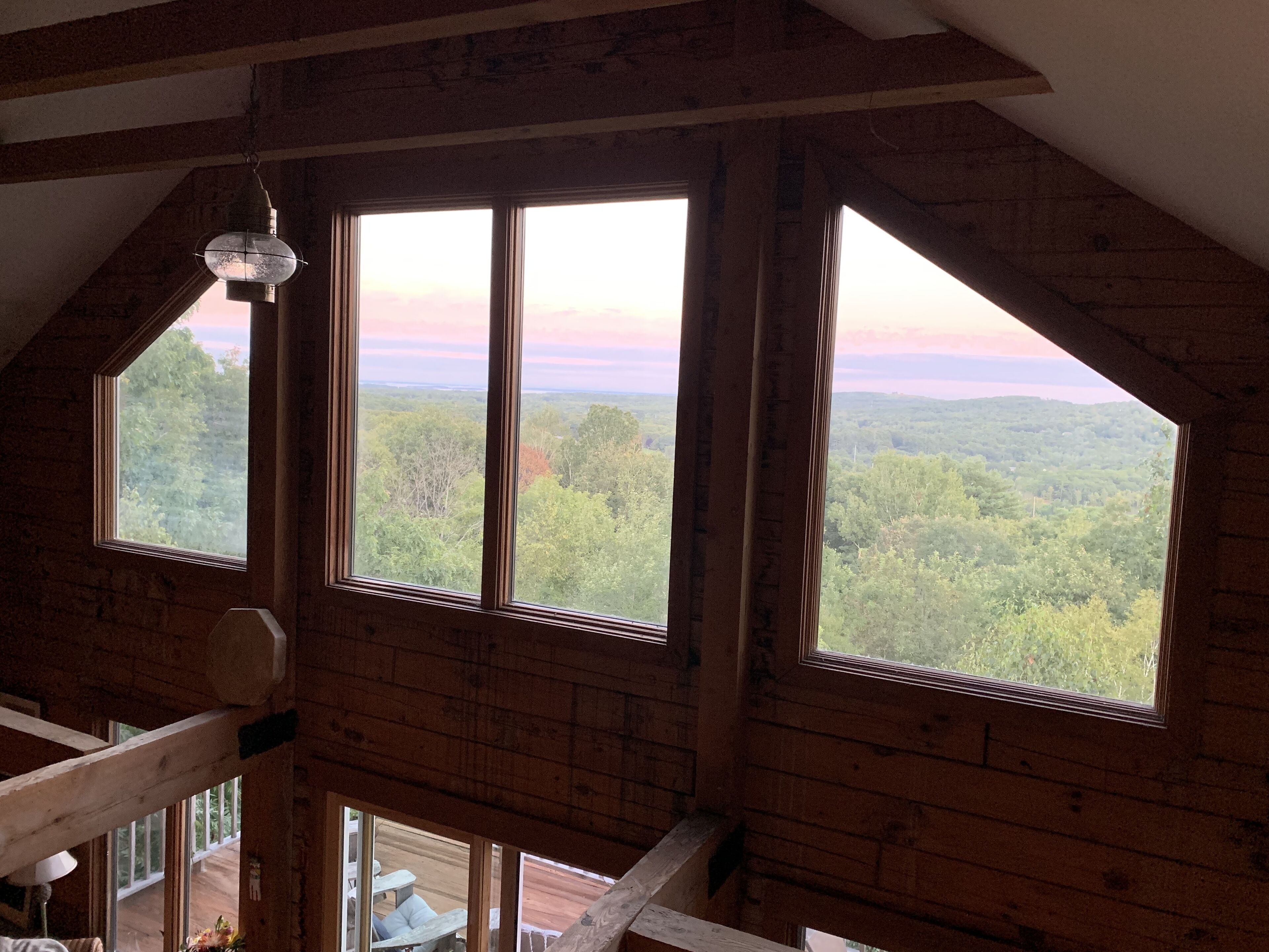 Ein Zimmer mit großem Fenster und Blick auf eine bewaldete Landschaft.