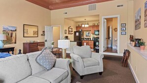 A spacious living room with a high ceiling and hardwood trim, a kitchen in the background, and a dining area. - Stay in Crozet Mountain Suite in Downtown Crozet (Crozet)