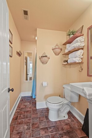 Bathroom features a classic design with a white toilet, sink, and bathtub, complemented by decorative wall sconces and a towel rack.