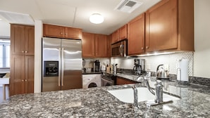A kitchen with granite countertops, stainless steel appliances, wooden cabinets, and a tiled backsplash.