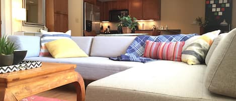 A living room with a sofa, a wooden coffee table, and a red floral rug.