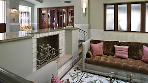 A living room with a fireplace, a sofa with cushions, and a patterned rug.