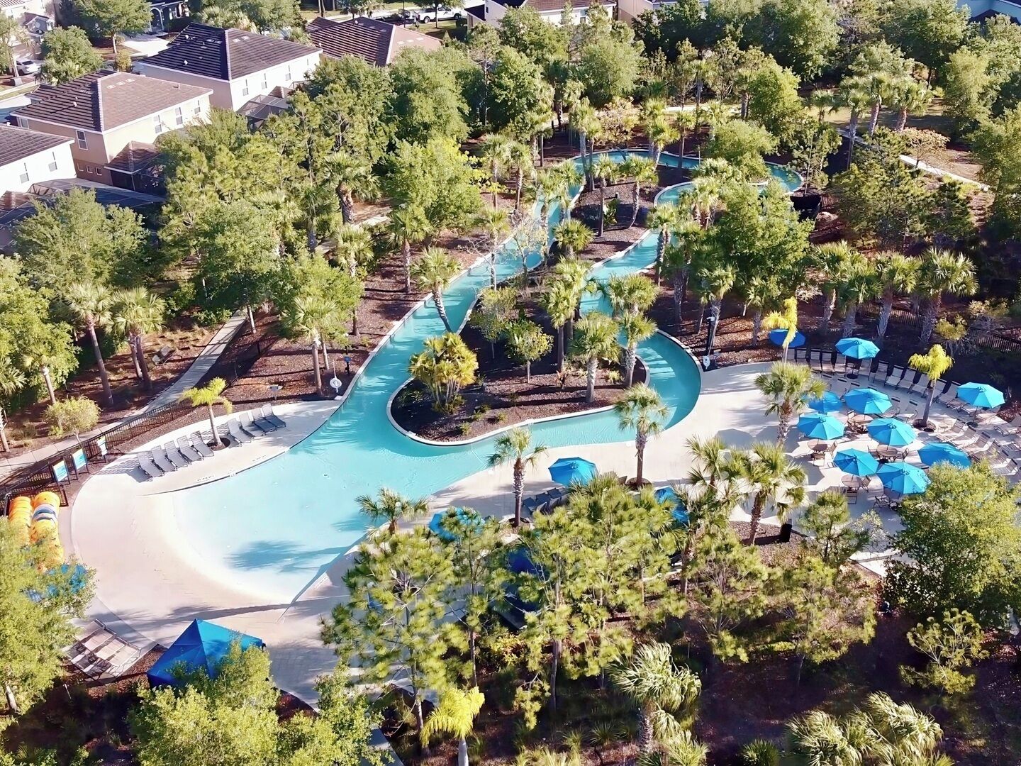 Ein Resort mit einem gewundenen Pool, Liegebereichen und tropischer Bepflanzung.