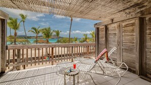 Ein Balkon mit Blick auf das Meer, ein Hollerleger, ein Metallstuhl und ein kleiner Tisch mit einem Getränk.