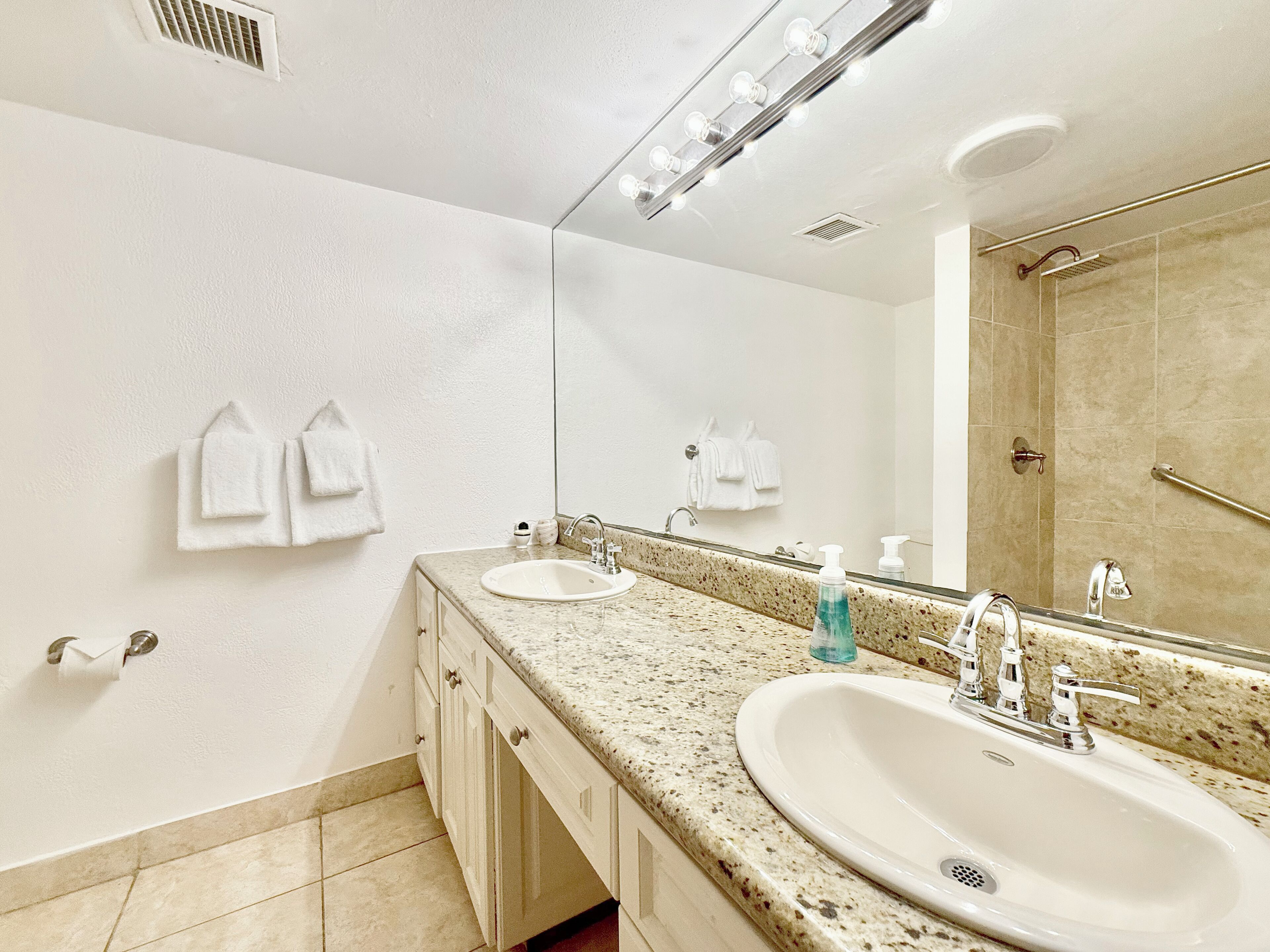 Un baño con dos lavamanos, un espejo grande y una zona de ducha.