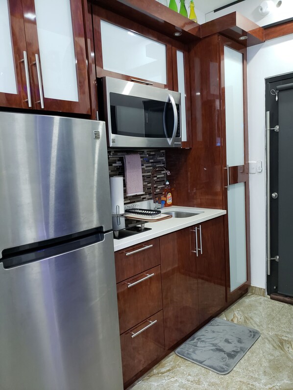 A kitchen with stainless steel appliances, wooden cabinets, a microwave, and a sink. - Apt102 Beachfront Studio Steps to The Beach (Isla Verde Carolina)