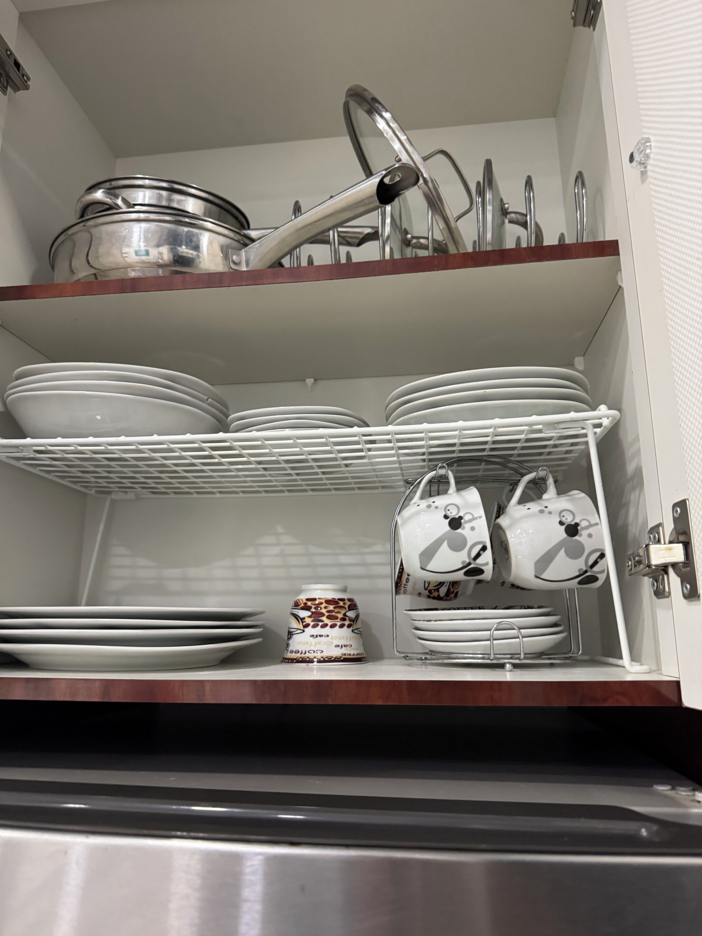 Una cucina con mensole bianche piene di piatti, ciotole e una caffettiera.