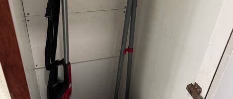 A small room with a white door, a blue cooler, and a red and black vacuum cleaner.