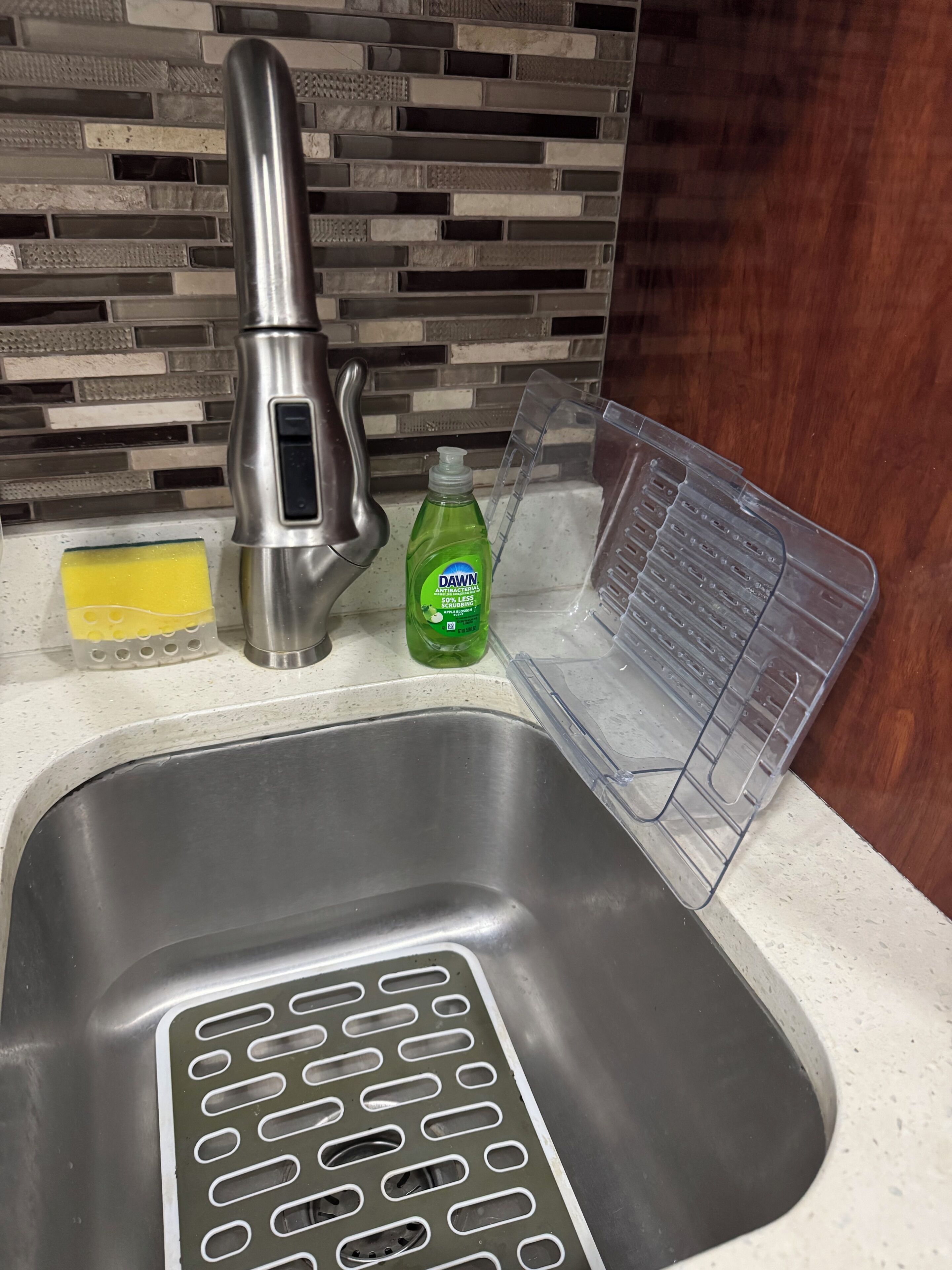 A kitchen sink with a modern faucet, a dish soap bottle, and a sponge.