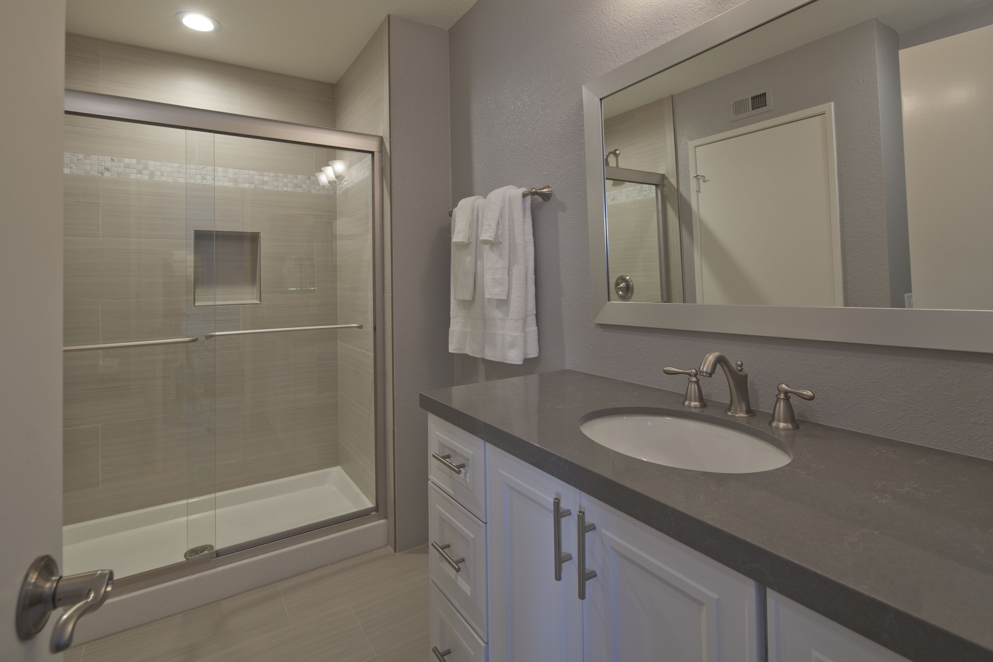 Une salle de bain moderne avec une douche à parois de verre, un lavabo avec un meuble-vasque et un grand miroir.