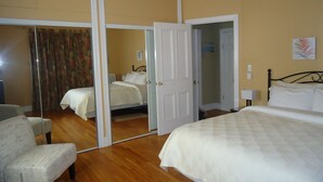 Une chambre d’hôtel avec un grand miroir, un lit, une chaise et une armoire.