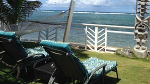 Un patio frente al mar con sillones de descanso y una hamaca con vistas al océano.