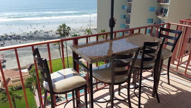 Un balcón con mesa y sillas con vistas a la playa.