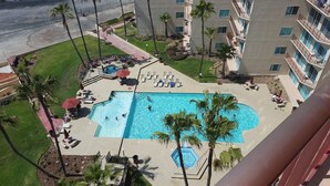 Un hotel con una amplia piscina rodeada de sillas de descanso y palmeras.