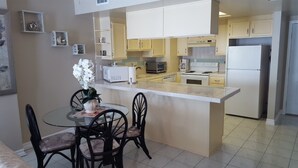 Una cocina moderna con armarios blancos, una isla central y un comedor con sillas.