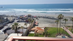 Un resort en la playa con vista al océano, un área de piscina y varios edificios con balcones.
