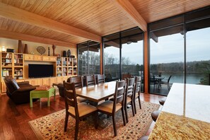 Relax in a spacious open-plan living space with a dining table and comfortable seating, a cozy seating area with a sofa and flat-screen TV, and a view of the surrounding landscape.