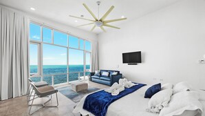 A modern bedroom with a large bed, a view of the ocean, a ceiling fan, and a flat-screen TV. - Luxury Ocean Front Villa with Heated Infinity Pool, Private Pier and Kayaks (Cabo Rojo)