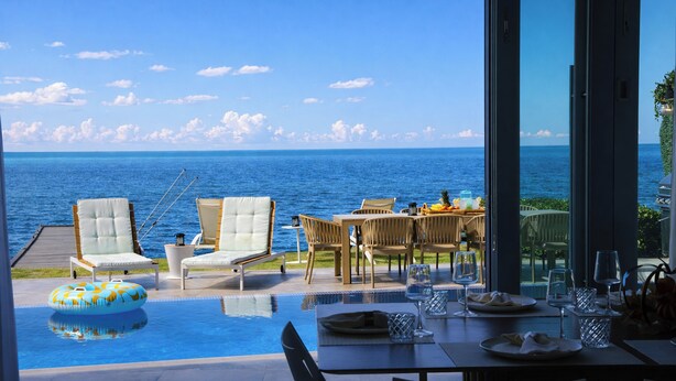 An infinity pool with a view of the ocean, outdoor seating, and a dining area with tables and chairs. - Luxury Ocean Front Villa with Heated Infinity Pool, Private Pier and Kayaks (Cabo Rojo)