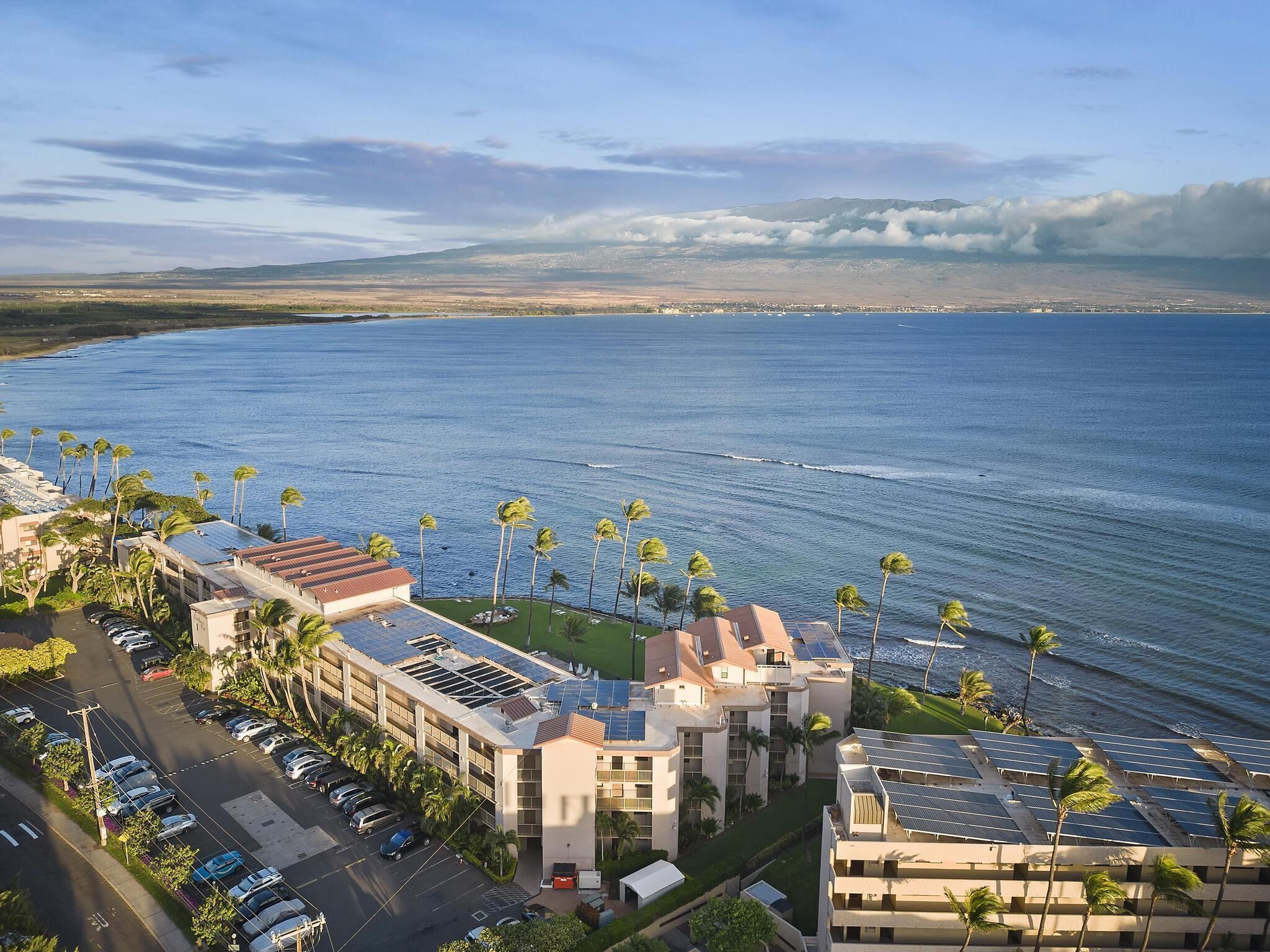 Un hotel sul lungomare con diversi edifici, un parcheggio e vista sull'oceano.