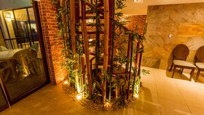 A reception area with a bamboo plant structure, a brick wall, and a stone wall.