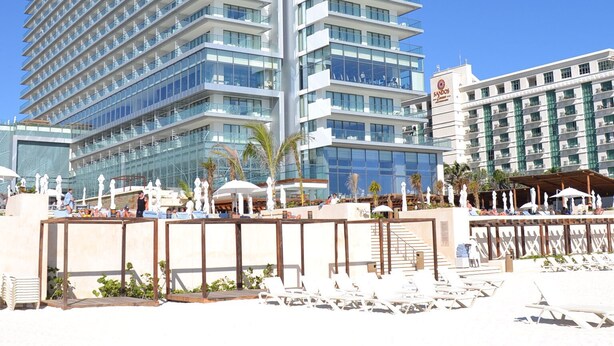 A high-rise hotel with multiple balconies and a pool area with sun loungers.