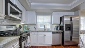 Una cocina moderna con armarios blancos, electrodomésticos de acero inoxidable y piso de madera.