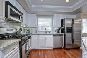 Una cucina moderna con mobili bianchi, elettrodomestici in acciaio inossidabile e pavimento in legno.