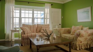 A living room with two sofas, a coffee table, and a window with curtains.
