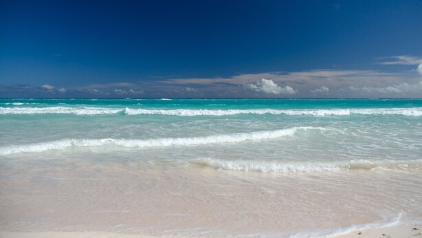 A beach with clear turquoise water and a sandy shore.