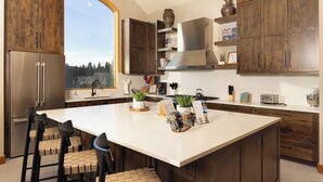 A modern kitchen with wooden cabinets, a large island, and a view of the outdoors. - Moosehead Lodge: Clear Mountain Views, Hot Tub & Game Room (Breckenridge)