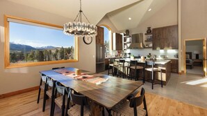 A spacious kitchen with wooden cabinets, a large island, and a view of mountains through a window. - Moosehead Lodge: Clear Mountain Views, Hot Tub & Game Room (Breckenridge)
