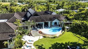 A large house with a swimming pool, solar panels, and a well-maintained lawn.