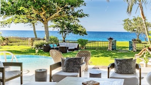 A poolside area with outdoor seating, a view of the ocean, and a well-maintained lawn. - Exclusive Oceanfront Villa in Charming Jamaican North Coast Resort Town (St. Ann)
