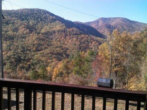 Une vue sur la montagne, avec une terrasse en bois et une petite construction ressemblant à un chalet.