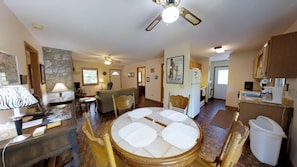 A spacious living room with a round table, a ceiling fan, and a kitchen area with a refrigerator and microwave. - Mountain View Cabin (Franklin)