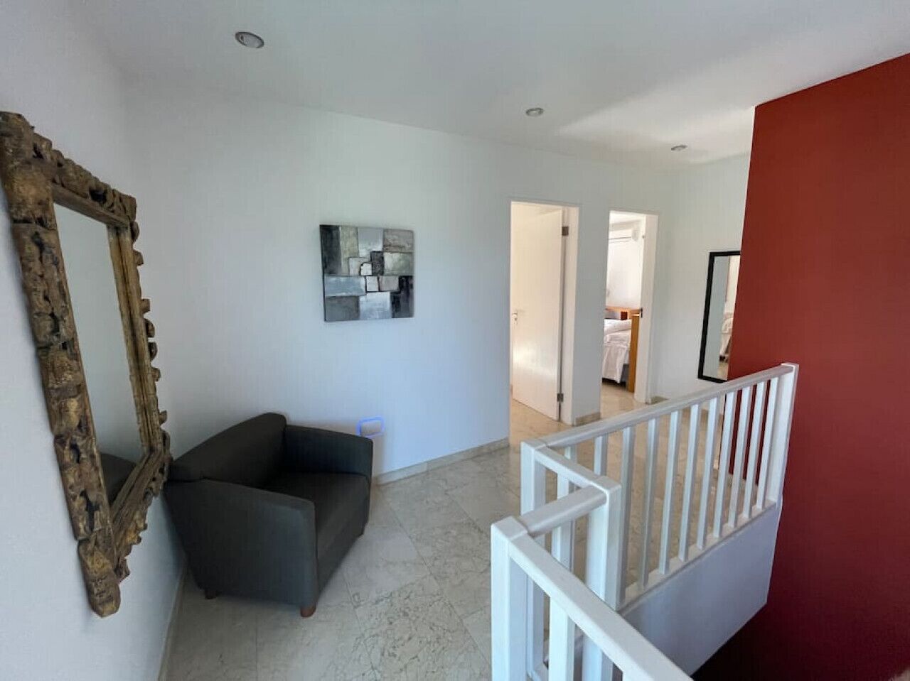 Ein modernes Wohnzimmer mit einem dunklen Sofa, einem dekorativen Spiegel und einem minimalistischen Kunstwerk an der Wand.