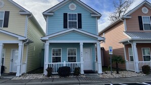 A row of townhouses with a central entrance, a front porch, and a small front yard with gravel. - 343 Sailors, Beautiful 2-bedroom cottage in Myrtle Beach, 2 Blocks to the Beach! (Myrtle Beach)