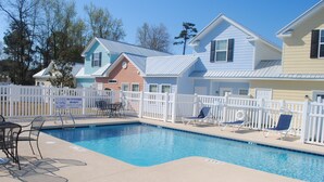 A swimming pool area with a pool, lounge chairs, and a white fence. - 343 Sailors, Beautiful 2-bedroom cottage in Myrtle Beach, 2 Blocks to the Beach! (Myrtle Beach)