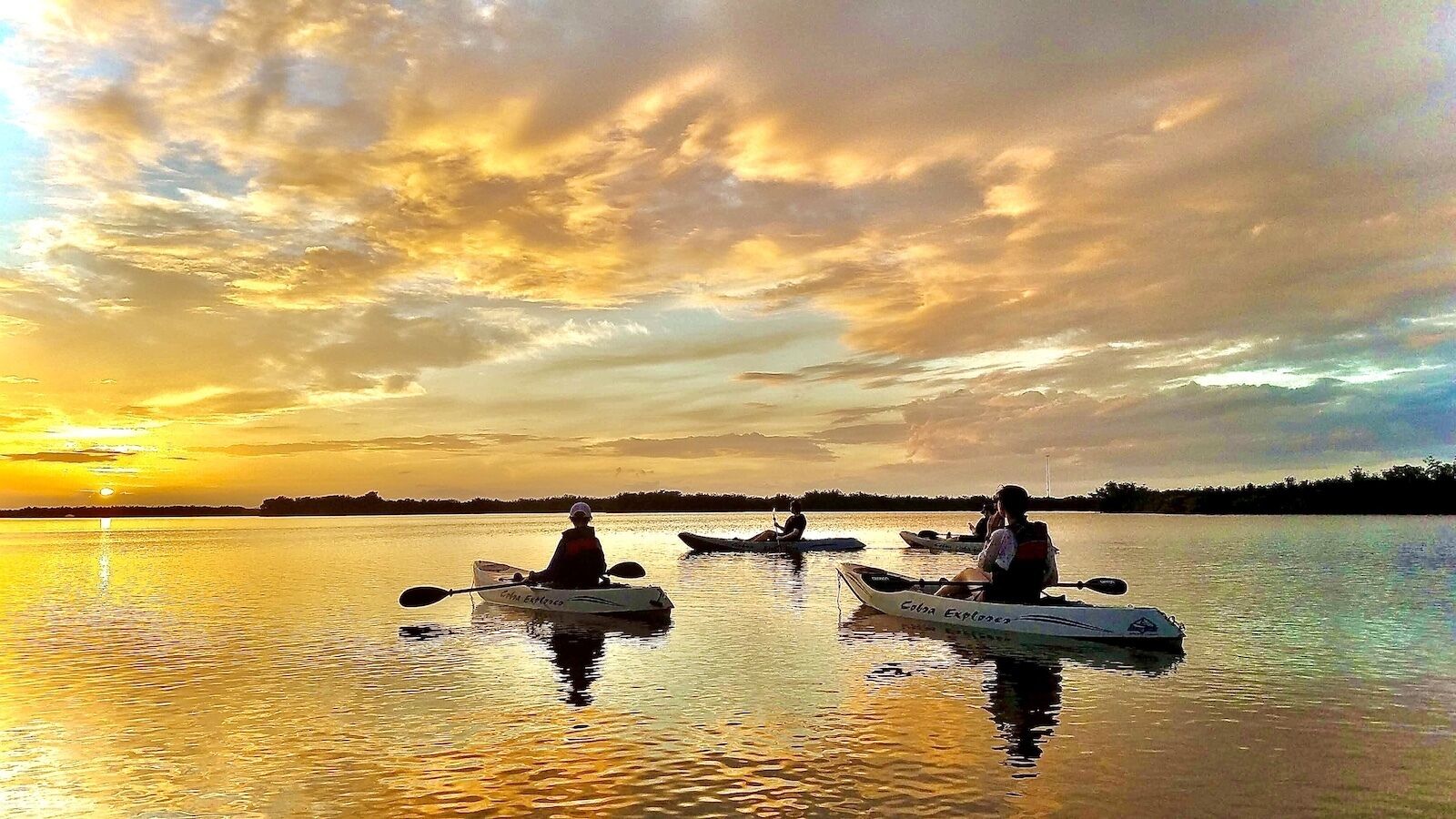 Three kayaks on calm water during sunset.