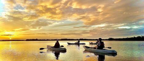Three kayaks on calm water during sunset.
